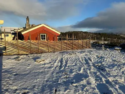 a red house with a fence in the snow at Sits in the middle of Reinheimen and Dovrefjell Rondane in Dombås