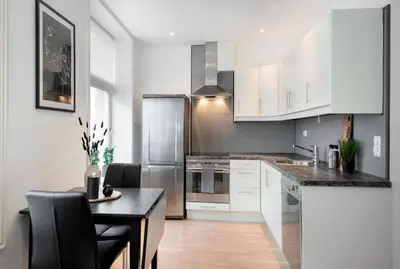 a kitchen with white cabinets and a table with chairs at Spacious 2-room in the city center, easy access to everything in Ålesund