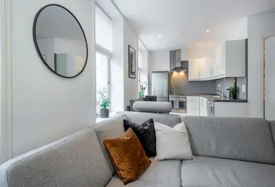 a living room with a gray couch and a mirror at Spacious 2-room in the city center, easy access to everything in Ålesund