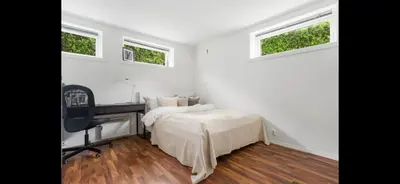 a bedroom with a bed and a desk and two windows at Central 4 room apartment in Bergen
