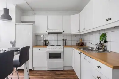 a kitchen with white cabinets and a white stove top oven at Central 4 room apartment in Bergen