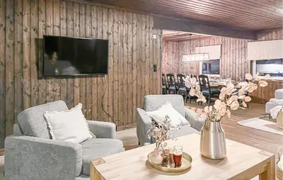 a living room with chairs and a table and a television at Lovely Home In Sjusjøen With Sauna in Sjusjøen