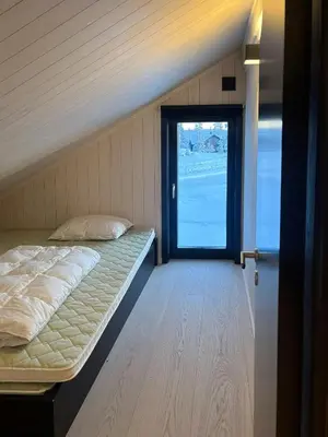 a room with a bed and a door with a window at Architect Cabin With Ski-In Near Trysil in Trysil