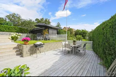 a patio with a table and chairs on a wooden deck at Spacious house with a beautiful view for rent in Ålesund