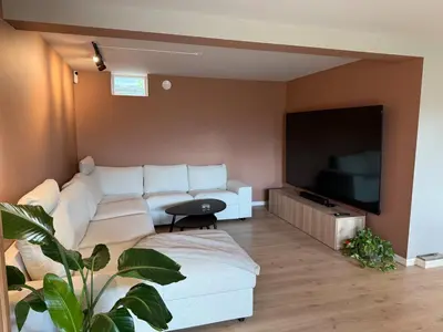 a living room with a white couch and a flat screen tv at Spacious house with a beautiful view for rent in Ålesund