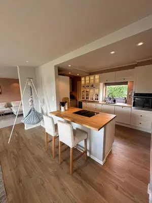 a kitchen with a wooden table and white chairs at Spacious house with a beautiful view for rent in Ålesund