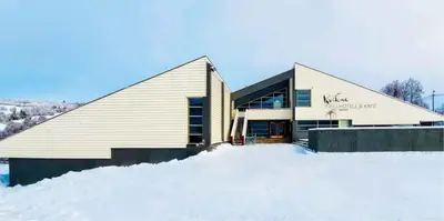 a large building in the snow next to a pile of snow at Kvikne Fjellhotell & Kafé in Tynset