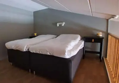 a bedroom with a large bed with white sheets at Kvikne Fjellhotell & Kafé in Tynset
