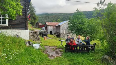 a group of people sitting on a bench in the grass at The old farm Lodge Lykkeslet