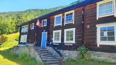 a wooden house with a flag on the side of it at The old farm Lodge Lykkeslet