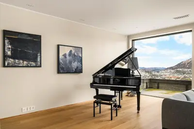 a black piano in a living room with a window at Bellevue Penthouse - Exclusive Design in Bergen