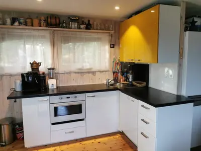 a kitchen with white cabinets and a black counter top at Cozy family cottage with a view