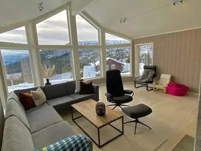 a living room with a couch and chairs and windows at High standard, large cabin with amazing view in Stryn