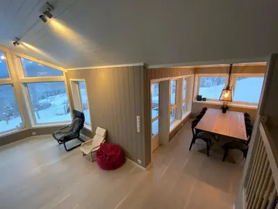 a living room with a table and chairs and windows at High standard, large cabin with amazing view in Stryn