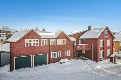 a red house with two garage doors in the snow at Apartment with garage in the center of Lillehammer in Lillehammer