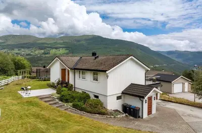 a white house with a mountain in the background at Bolig på Kaupanger in Kaupanger