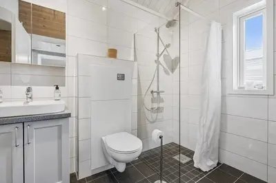 a white bathroom with a toilet and a shower at Modern family cabin with ski in out, central location in Beitostølen in Beitostøl