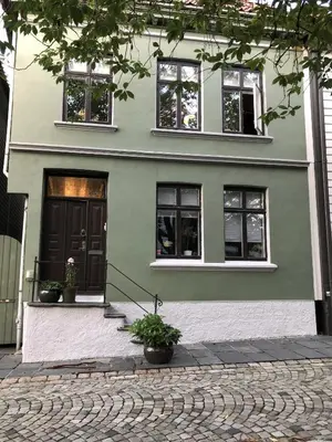 a green house with black doors and windows at City apartment in Bergen in Bergen