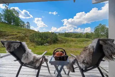 two chairs on a porch with a table and a bowl of fruit at Leilighet på Hovden in Bykle