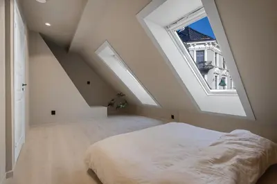 an attic bedroom with a bed and a window at Toppleilighet på Sandviken med balkong in Bergen