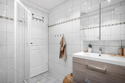 a white bathroom with a sink and a shower at Toppleilighet på Sandviken med balkong in Bergen