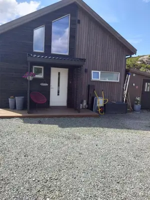 a black house with a white door and a red chair at Holiday home near all facilities in Grinde, Aksdal in Tysvær
