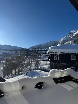 a house covered in snow with mountains in the background at Cozy ski in&out cabin Hemsedal in Hemsedal