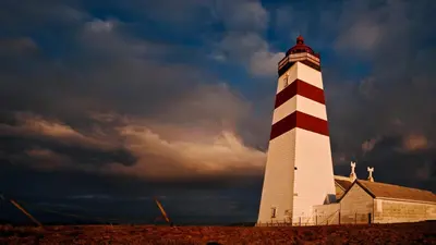 a lighthouse with a red and white stripe on it at Alnes Gård in Ålesund