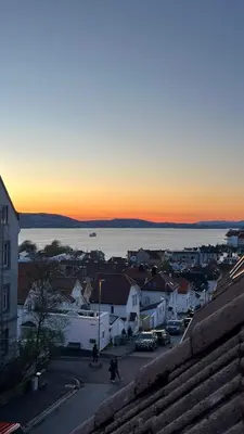 a view of a town with the sunset in the background at Cozy loft apartment in the heart of Bergen in Bergen