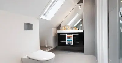 a bathroom with a toilet and a sink and a skylight at Cozy loft apartment in the heart of Bergen in Bergen