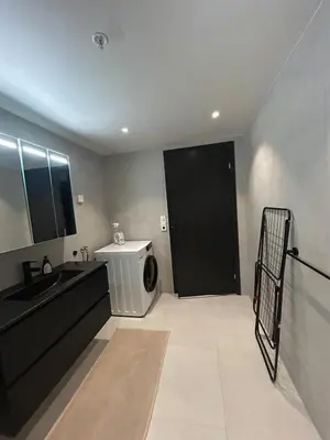 a bathroom with a washing machine and a black door at Great apartment in the center of Ålesund in Ålesund