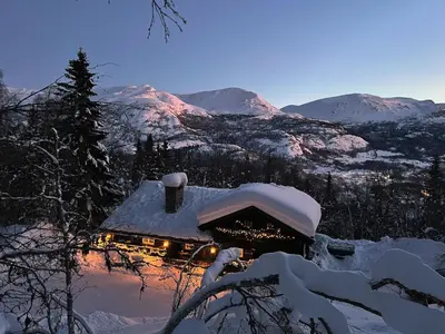 a house covered in snow with mountains in the background at Skogstad Lodge, Hemsedal in Hemsedal