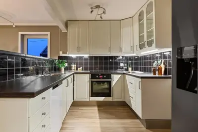a kitchen with white cabinets and black appliances at Central apartment with parking in unique surroundings in Bergen