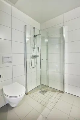 a white bathroom with a shower and a toilet at Hjorten Hotell Hitra in Fillan