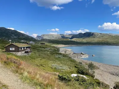 a house on a hill next to a lake at Ski-in & out Totten Lodge apartment two bedrooms in Hemsedal