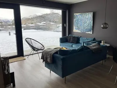 a living room with a blue couch and a large window at Ski-in & out Totten Lodge apartment two bedrooms in Hemsedal