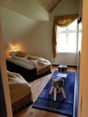 a bedroom with a bed and two chairs and a window at Rødseter Gjestegård in Fjarland