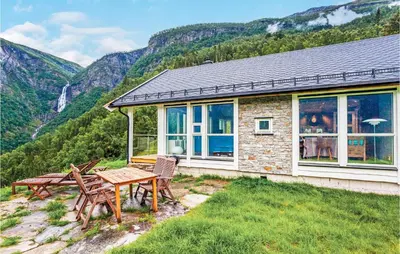 a house with a picnic table and chairs and mountains at 4 Bedroom Stunning Home In Skjolden in Skjolden