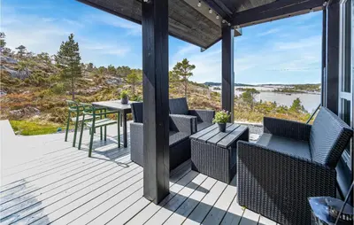 a deck with chairs and a table with a view of the water at 4 Bedroom Nice Home In Tustna in Leira