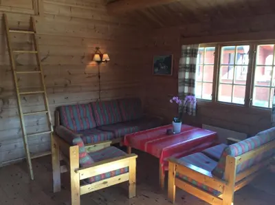 a living room with couches and a table and a ladder at Furuly Camping in Nordberg