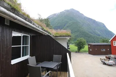 a patio with a table and chairs and a mountain at Setnes Feriesenter in Veblungsnes