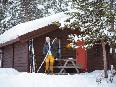 a man standing in the snow in front of a cabin at Sjodalen Hyttetun og Camping in Stuttgongfossen
