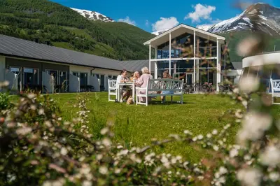 a group of people sitting at a table in front of a building at Valldal Fjordhotell - by Classic Norway Hotels in Valldal