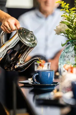 a tea kettle pouring tea into a blue cup at Valldal Fjordhotell - by Classic Norway Hotels in Valldal