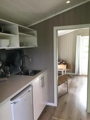 a kitchen with white cabinets and a sink and a table at Dalen Gaard camping og hytter in Geiranger