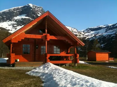 a log cabin in the mountains with snow at Dalen Gaard camping og hytter in Geiranger