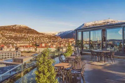 a balcony with tables and chairs overlooking a city at Prize by Radisson, Solheimsviken Bergen in Bergen