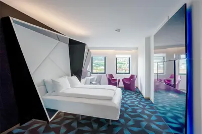 a bedroom with a white bed and purple chairs at Prize by Radisson, Solheimsviken Bergen in Bergen