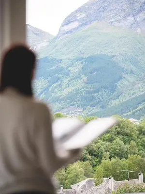 a man is looking out of a window at a mountain at Trolltunga Aparthotel in Tysso