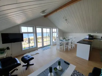 a living room with a kitchen and a table with chairs at Lauvøy Feriesenter in Askøy